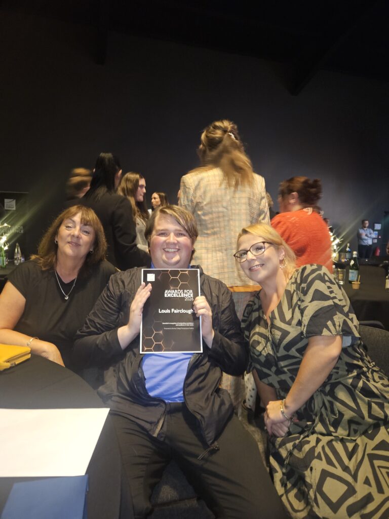 Louis holds his award, sitting with Sarah and Maria from Project Search.